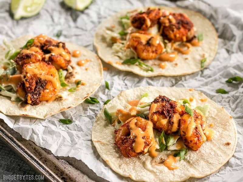 Seitenansicht von geschwärzten Garnelen-Tacos mit Knoblauch-Limetten-Sauce beträufelt