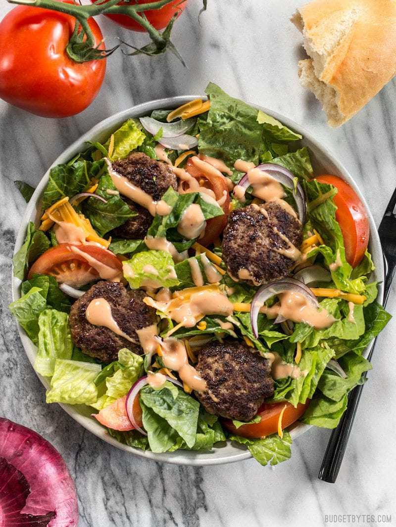 a huge fresh Cheeseburger Salad with animal sauce dressing drizzled over top