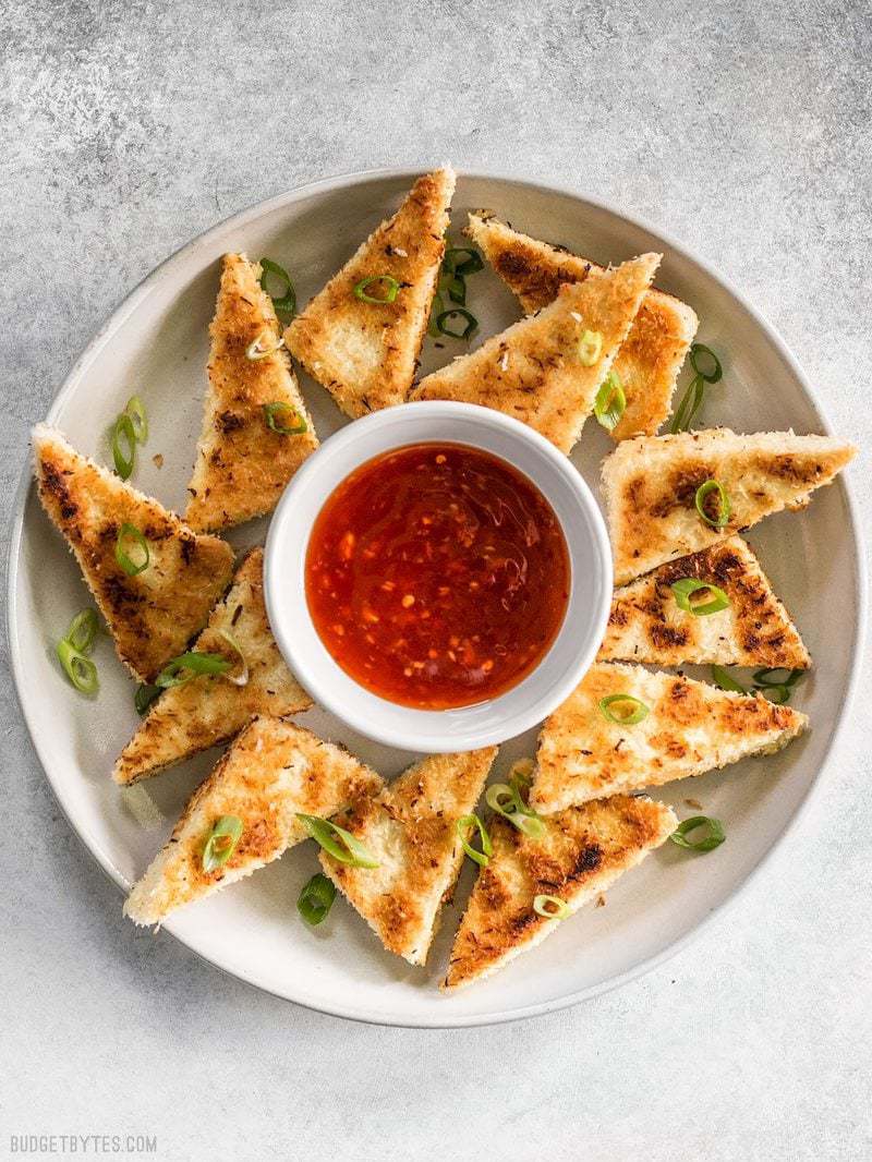 A large plate full of Coconut Crusted Tofu with a small bowl of sweet chili sauce in the middle