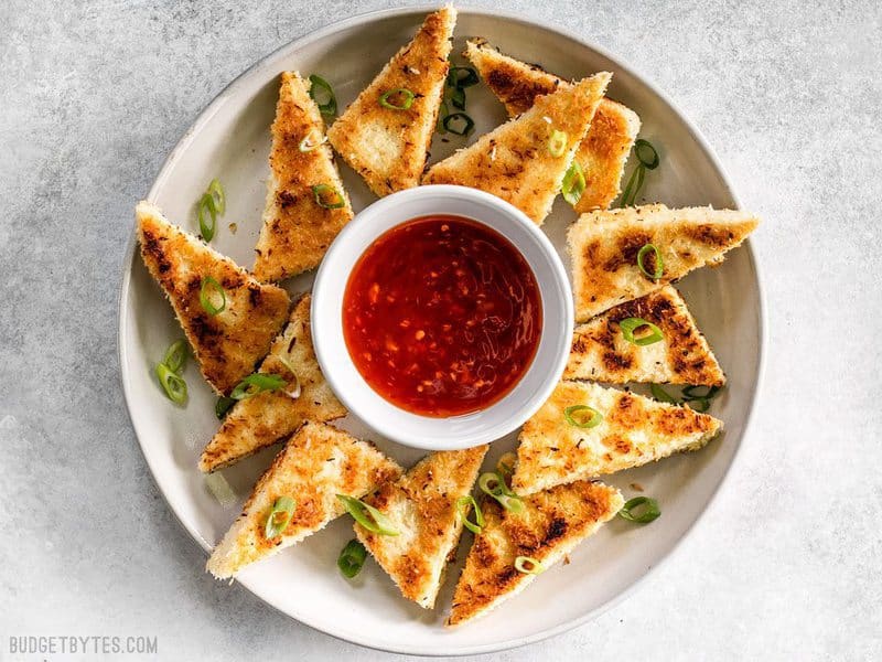 A plate full of Coconut Crusted Tofu dippers with a small bowl of sweet chili sauce in the center