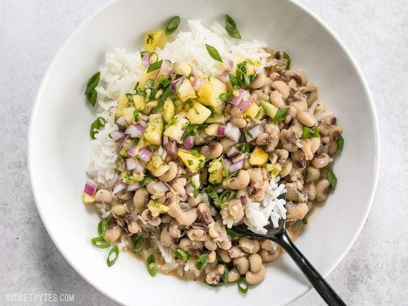 A bowl full of spicy Coconut Jerk Peas with pineapple salsa and jasmine rice
