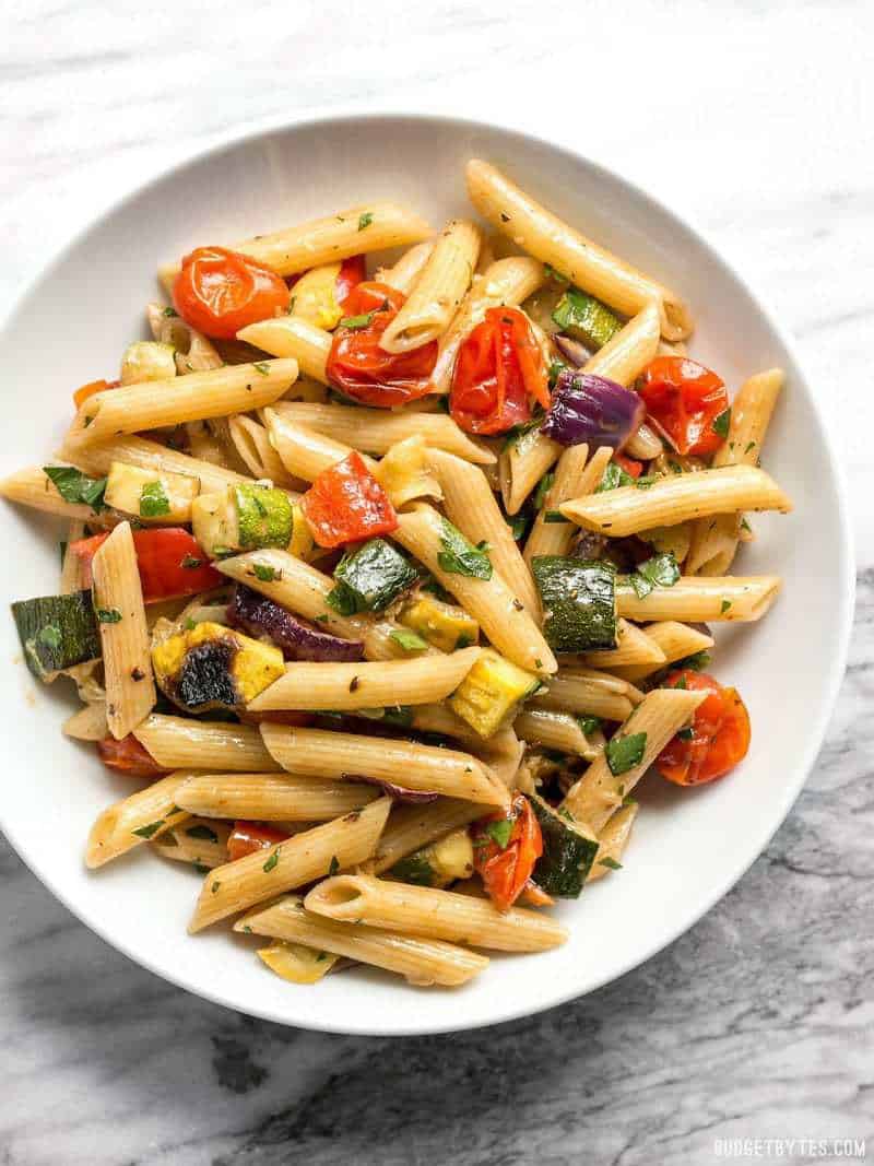 A big white bowl of Grilled Vegetable Pasta Salad on a marble countertop 