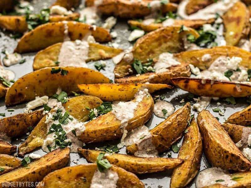 These simple Roasted Potato Wedges are the perfect vehicle for this creamy, garlicky shawarma sauce and crumbled feta. BudgetBytes.com Sheet pan of Roasted Potato Wedges with Shawarma Sauce from the front