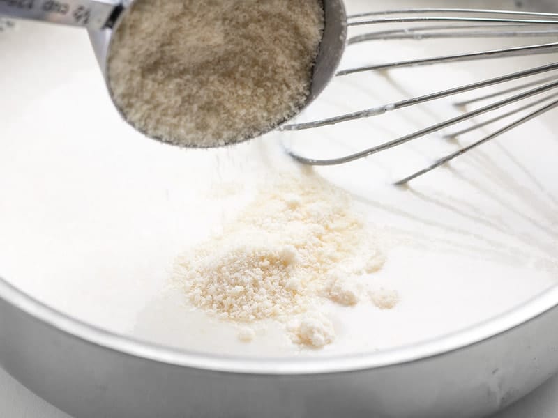 Grated Parmesan being added to garlic cream sauce