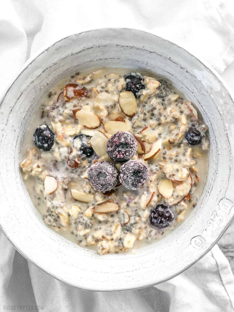 A bowl of Blueberry Almond Overnight Oats with a few frozen blueberries and almond slices on top for garnish