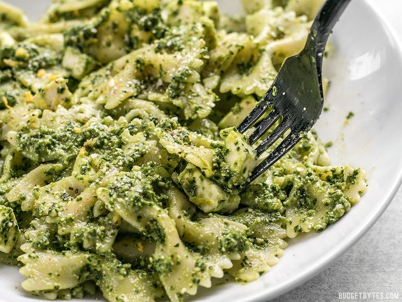 Close up of a fork picking up some Kale Pesto Pasta with mozzarella chunks