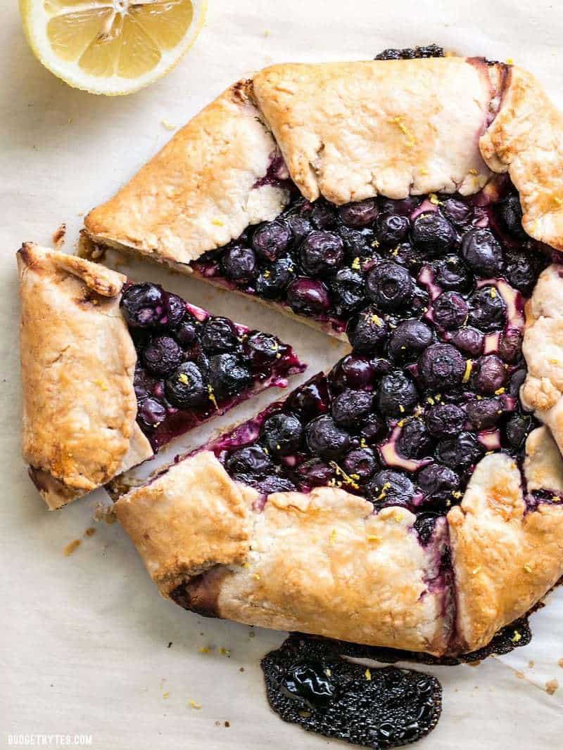 A freshly baked Lemon Blueberry Cream Cheese Galette on parchment paper, with fresh lemon zest sprinkled on top.