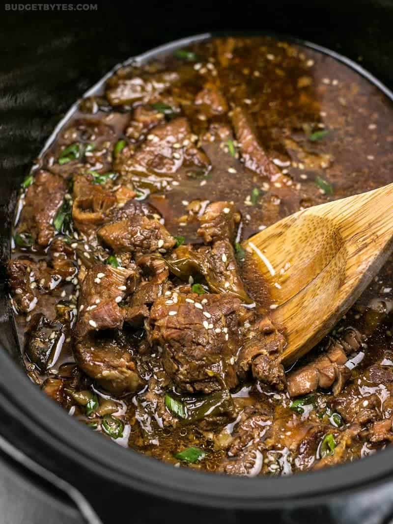 Slow Cooker Sesame Beef in the slow cooker with a wooden spoon