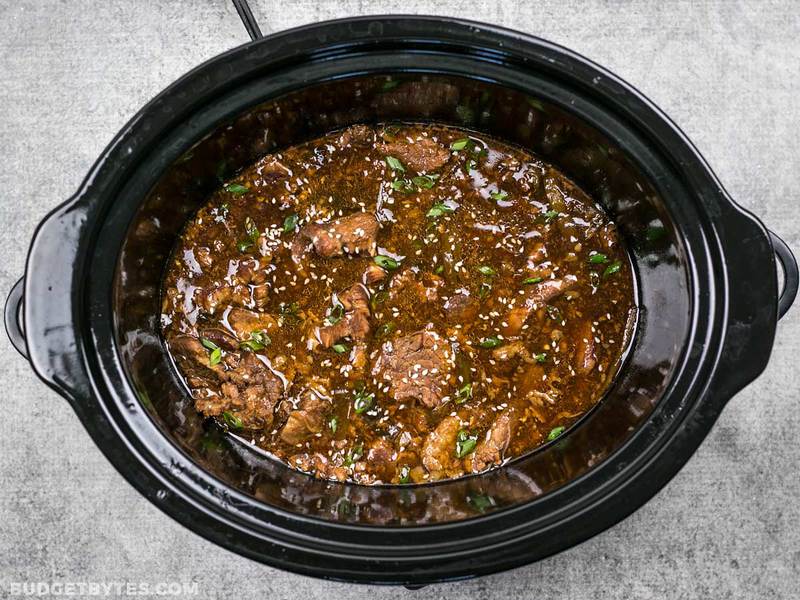 Slow Cooker Sesame Beef in the slow cooker garnished with green onion and sesame seeds