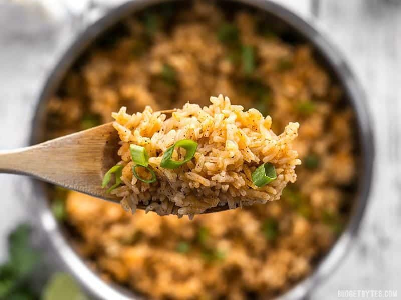 Close up spoonful of Taco Rice with the pot full in the background