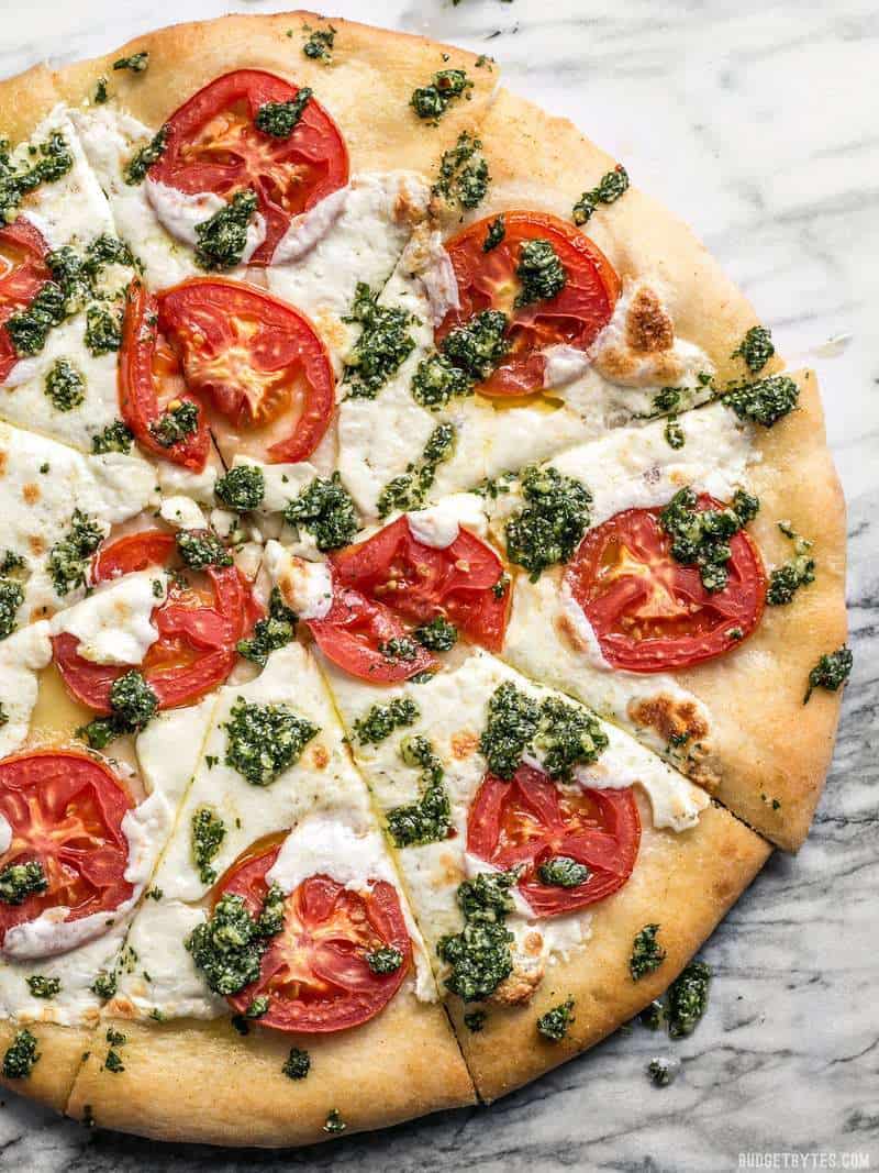 Close up of freshly baked white pizza with parsley pesto drizzle, sliced