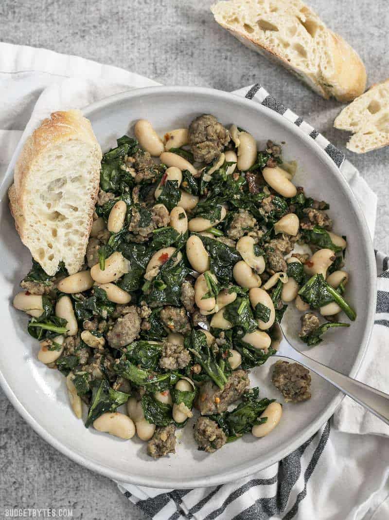 It doesn't get easier than this high protein, high fiber, high FLAVOR Italian Sausage and White Bean Skillet! BudgetBytes.com A bowl of Italian Sausage and White Beans with slices of baguette on the side