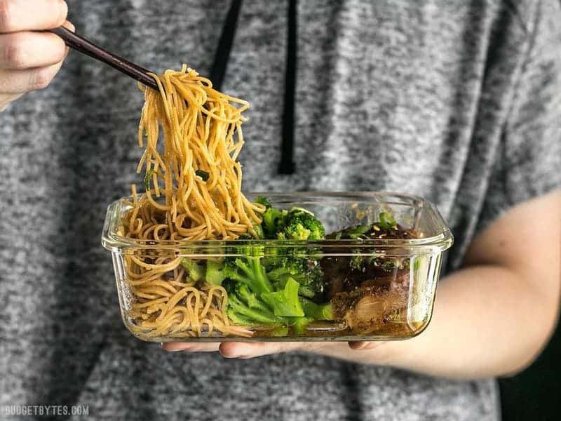 Garlic noodles being eaten out of the Sticky Ginger Soy Glazed Chicken Meal Prep container