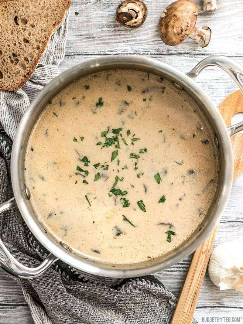 A pot full of Creamy Garlic Mushroom Soup with crusty bread nearby for dipping.