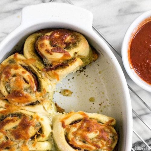 These Pesto Pizza Rolls are a fun way to change up your pizza routine with swirls of cheese, pesto, and pepperoni, plus lots of crispy edges! BudgetBytes.com
