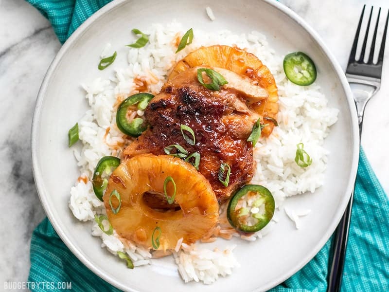 Pineapple BBQ Chicken on a plate with rice with green onion and jalapeño sprinkled over top.