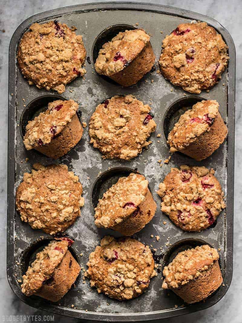 These Orange Cranberry Muffins with streusel topping are a holiday staple and extras can be frozen for a quick treat whenever the craving hits. BudgetBytes.com A muffin tin full of baked Cranberry Orange Muffins, view from above.
