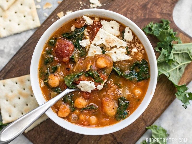 A bowl of Smoky Potato Chickpea Stew with crackers, being eaten. 