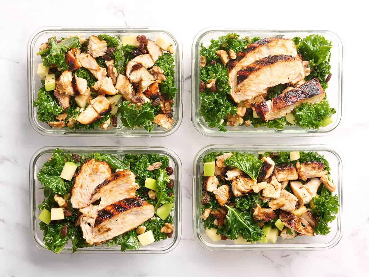 Overhead view of an easy kale salad with grilled chicken in meal prep containers.