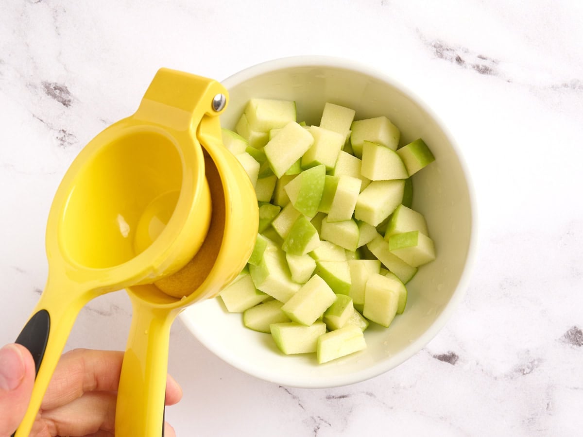 Lemon juice being squeezed into apples.