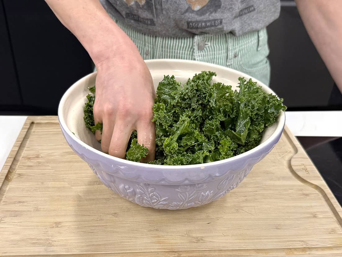 Kale being massaged in a bowl.