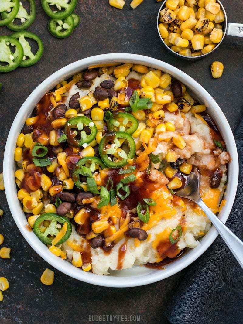 A huge bowl of Loaded Mashed Potatoes with jalapeños and roasted corn on the side.