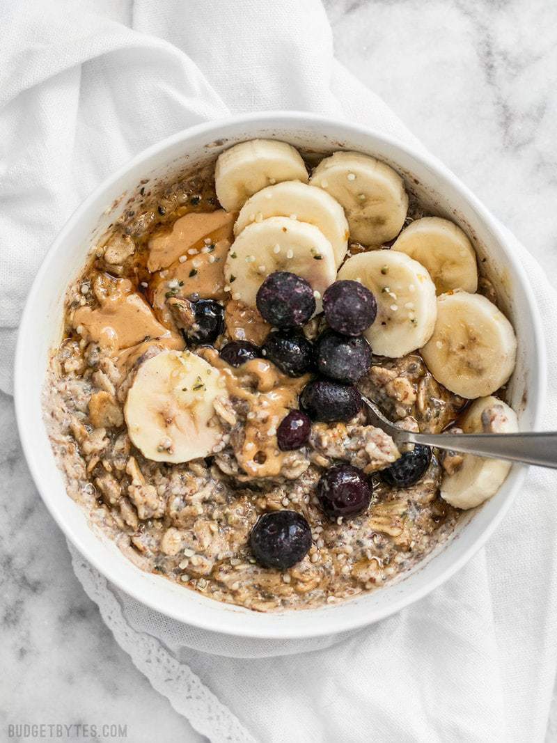 A bowl of Make Ahead Seeded Oats with bananas, blueberries, and peanut butter