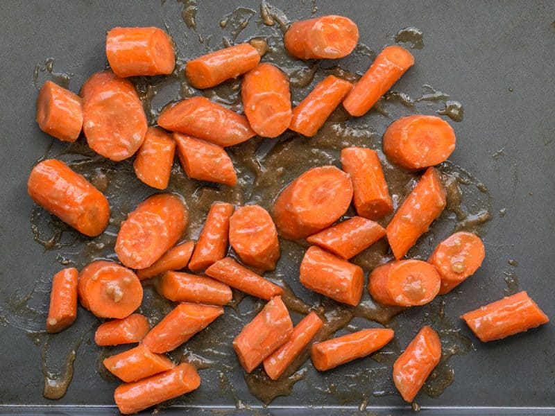 Carrots tossed in maple miso butter ready to roast