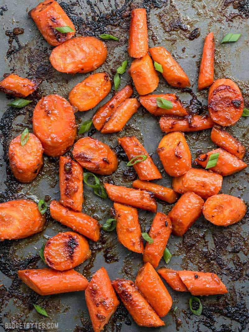 Close up of Maple Miso Roasted Carrots on a baking sheet with green onions