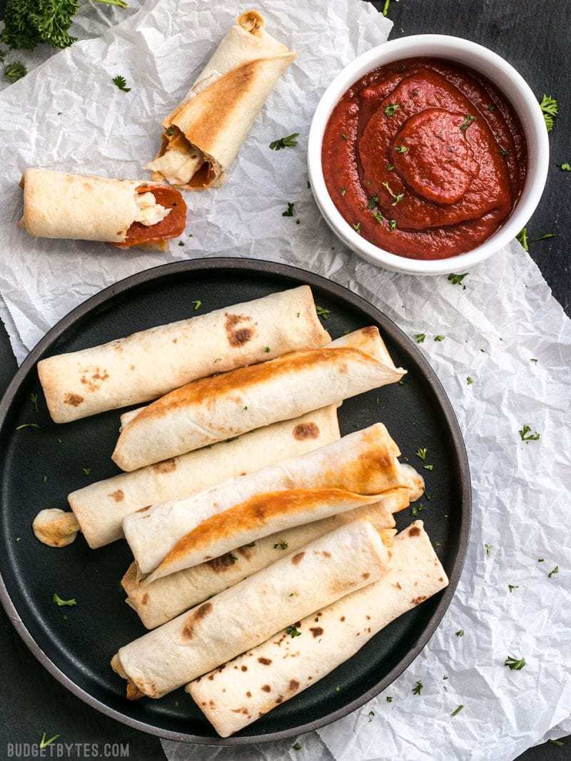 A plate full of Pizza Roll Ups with pizza sauce in a dish on the side.