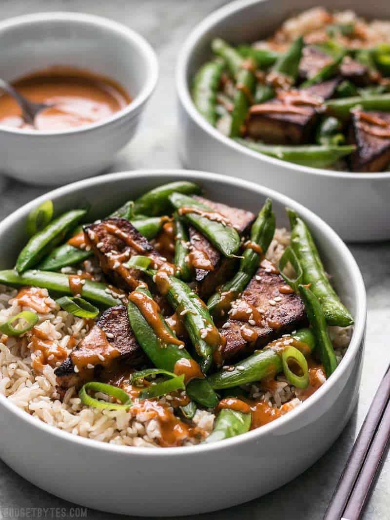 Two Soy Marinated Tofu Bowls with spicy peanut sauce in the background