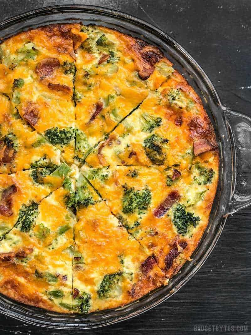 A close up view of Bacon Broccoli Cheddar Crustless Quiche baked in a glass pie plate. 