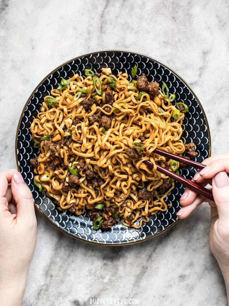 A big plate of Pork and Peanut Dragon Noodles being eaten with chopsticks