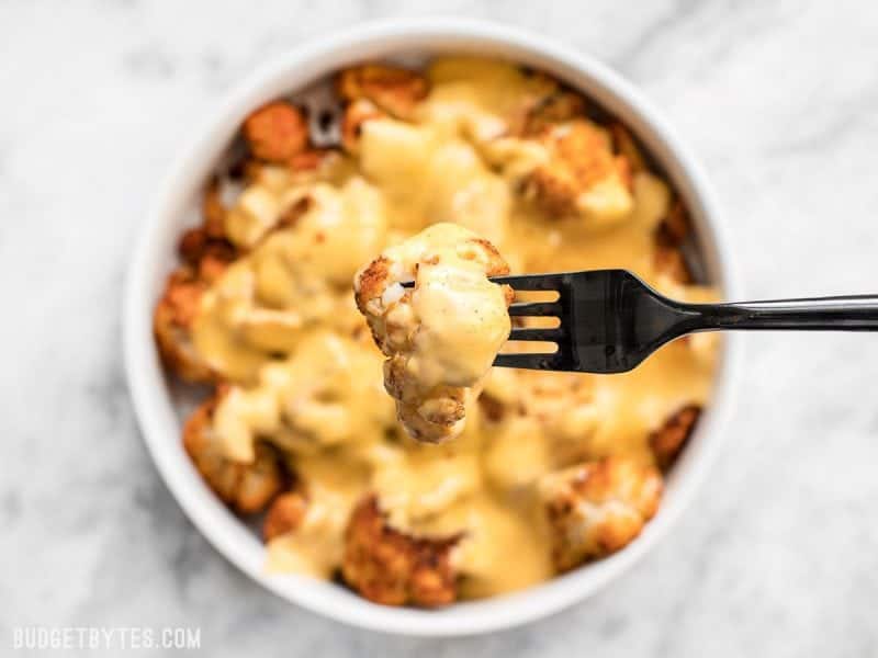 Close up of Spicy Roasted Cauliflower with Cheese Sauce on a fork