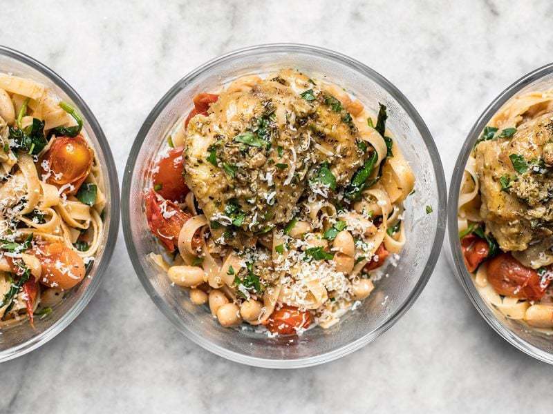 Glass meal prep containers lined up with Herb Butter Chicken and tuscan white bean pasta