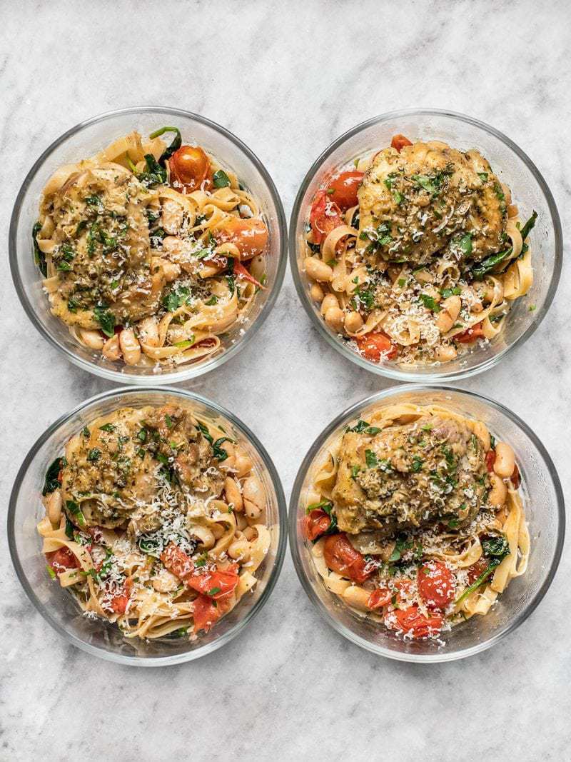 Four round glass meal prep containers with Herb Butter Chicken and Tuscan White Bean Pasta