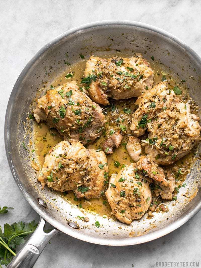 Herb Butter Chicken Thighs in a skillet with a buttery pan sauce and fresh parsley.