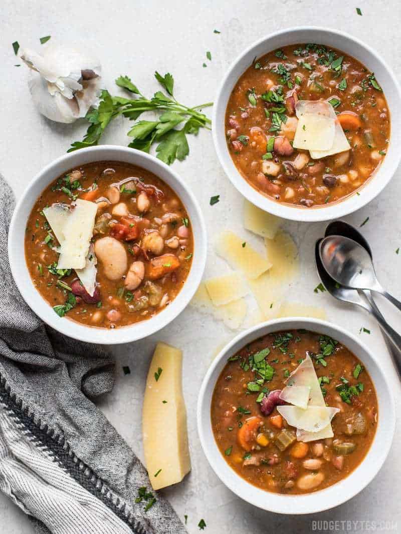 Three bowls of Vegetarian 15 Bean Soup topped with Parmesan and parsley