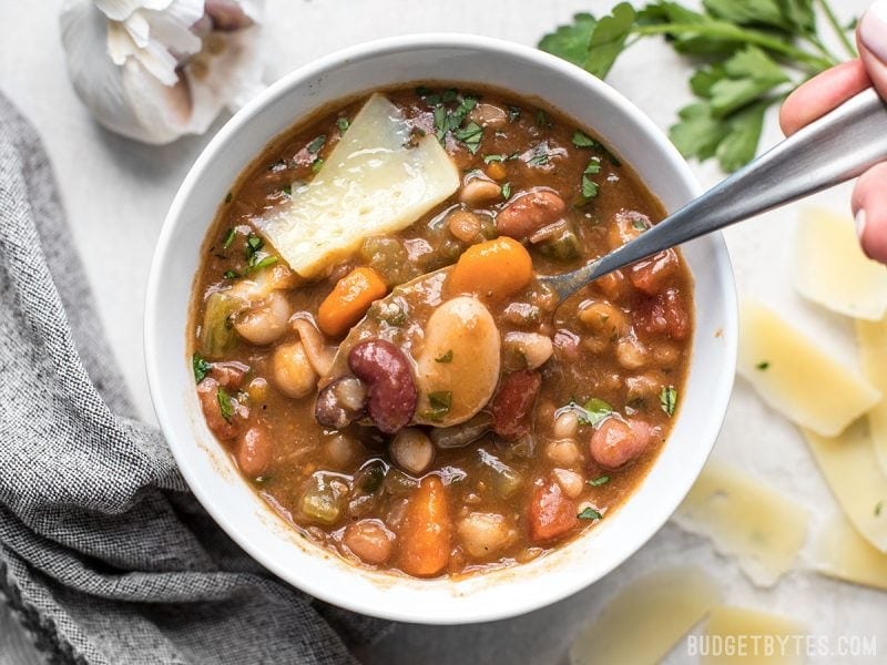 A spoon lifting beans out of a bowl of Vegetarian 15 Bean Soup 