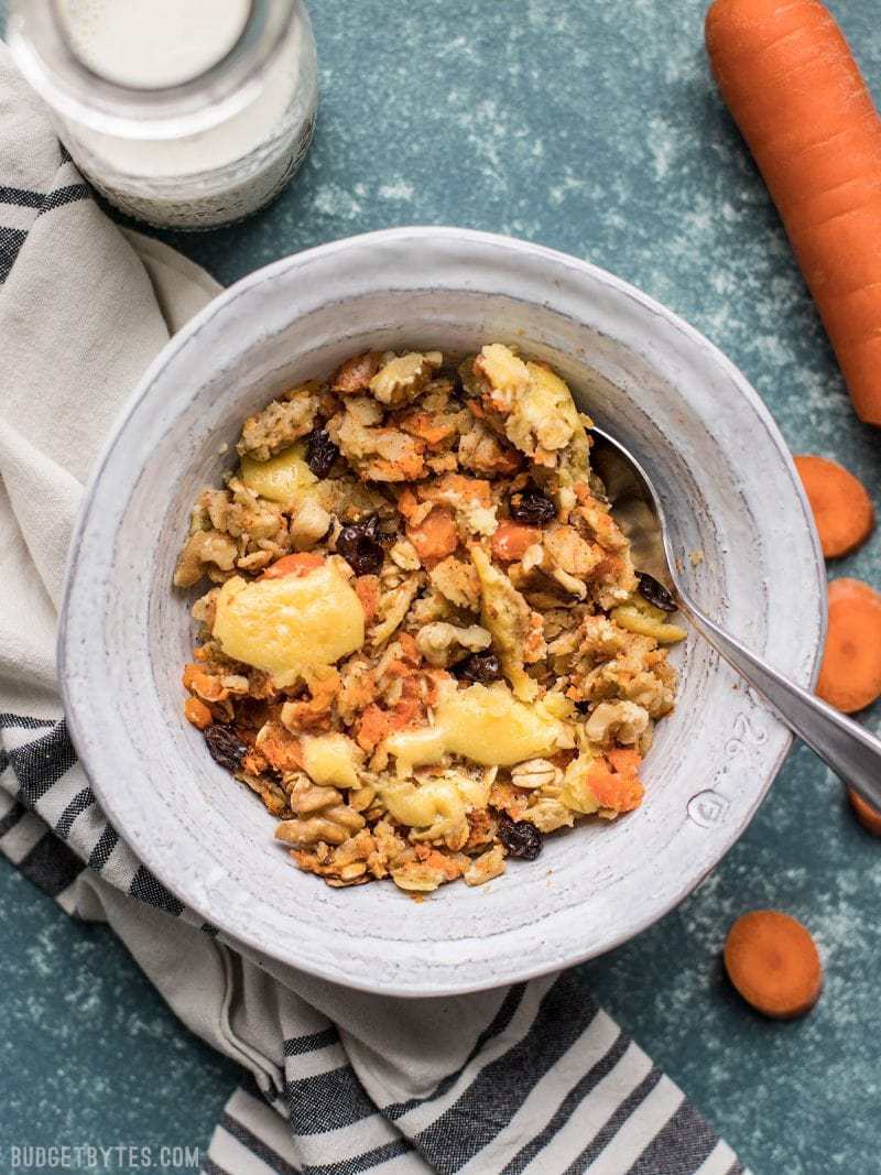 A bowl of Carrot Cake Baked Oatmeal with a bottle of milk and whole carrots near by. 