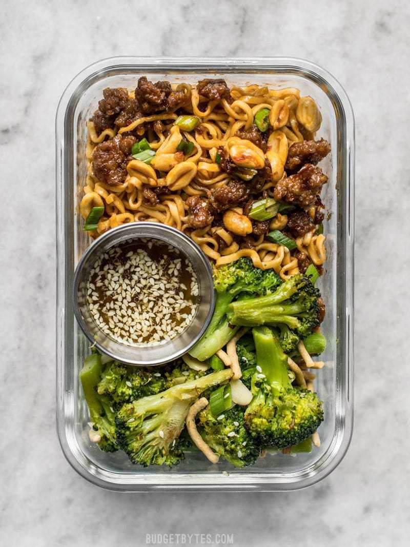 A glass meal prep container with Pork and Peanut Dragon Noodles and Broccoli Salad