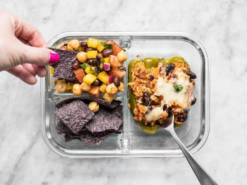 A chip being dipped into the Cowboy Caviar in the meal prep container