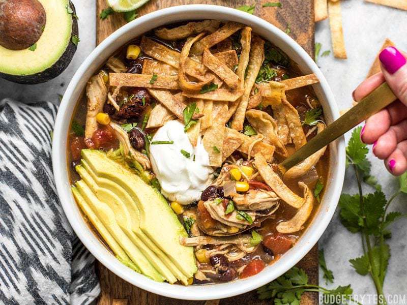 Someone taking a spoonful of Slow Cooker Chicken Tortilla Soup out of the bowl.