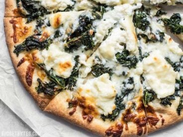 Garlicky greens and creamy ricotta pair perfectly on this light and fresh Garlicky Kale and Ricotta Pizza. It’s the perfect pizza for summer! BudgetBytes.com