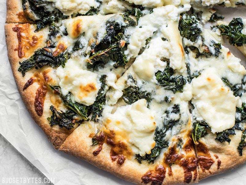 Close up view of browned crust and cheese on Garlicky Kale and Ricotta Pizza