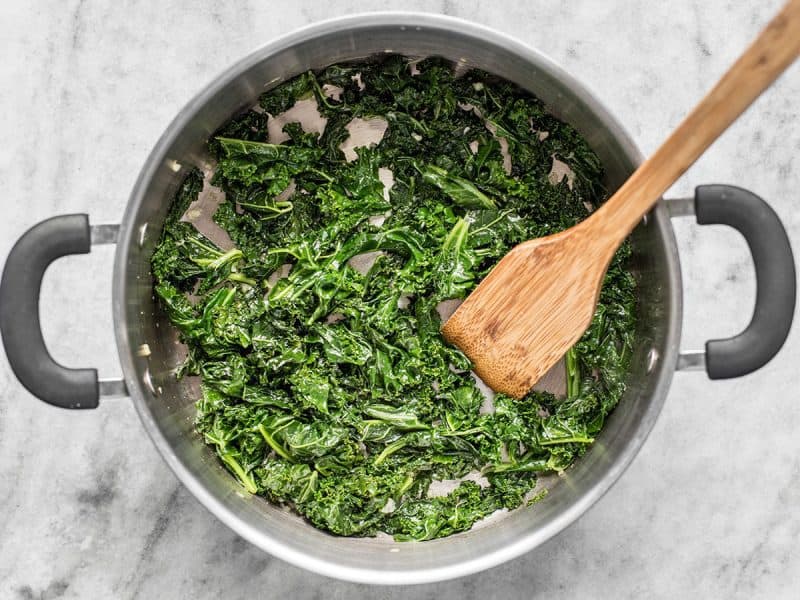 Sautéed Kale in the pot with a wooden spoon