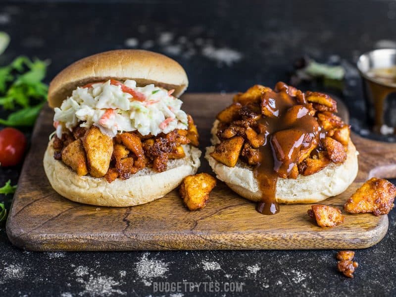 Front view of two BBQ Tofu Sliders on a wooden cutting board, sauce dripping down the front