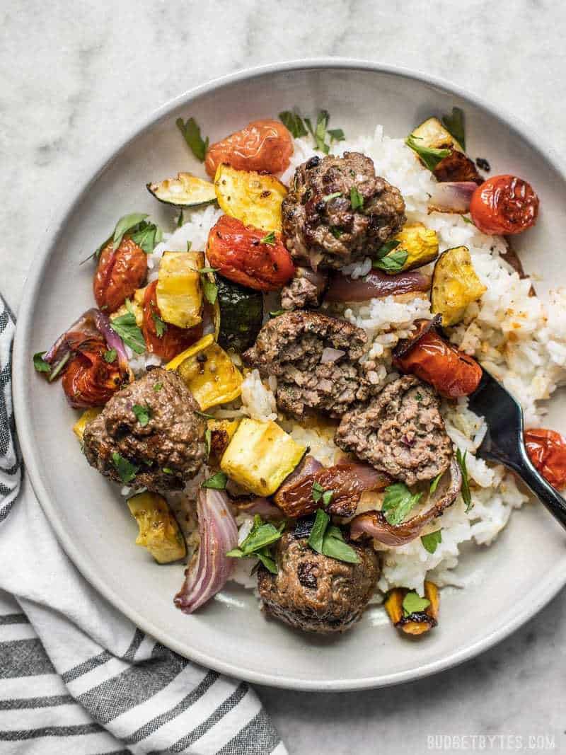 Beef Kofta Meatballs and Roasted Vegetables on a stoneware plate with rice and a black fork.