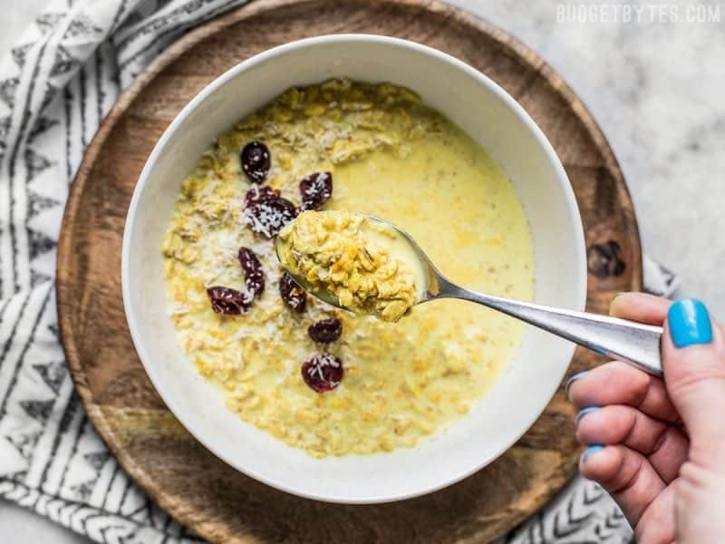 Bowl of golden milk overnight oats with a spoon 