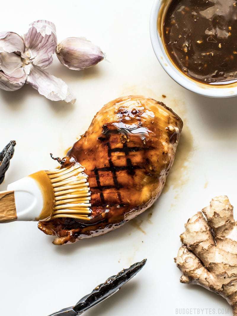 This Easy Homemade Teriyaki Sauce (or marinade) takes only a few minutes and five simple ingredients that can be kept on hand at all times. Perfect for last minute weeknight dinners! Budgetbytes.com Teriyaki Sauce being brushed onto a grilled chicken breast